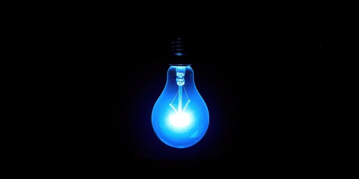 A blue light bulb is lit up in a dark room