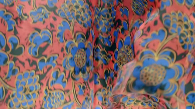 Red fabric with beautiful blue floral pattern falls, fluttering on a black background. Closeup. Macro. Closeup. Macro. Slow mo, slow motion, high speed camera, 200fps