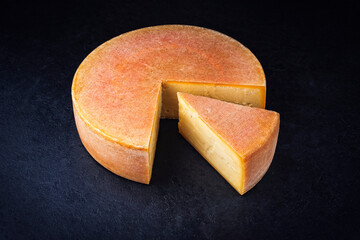 Traditional aged artisan mountain cheese of the European Alps offered as close-up on black rustic...