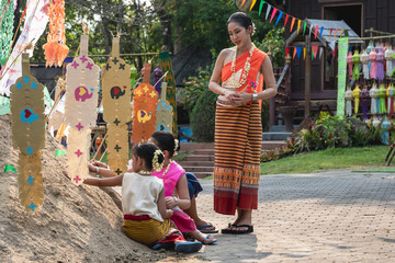 Fototapeta premium Thai woman and young girls in traditional Thai costume decorating sand pagoda celebrating Songkran 