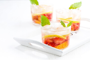 lemonade with strawberry and lemon on white tray, closeup