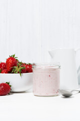 sweet strawberry yogurt and fresh berries on a white table, vertical