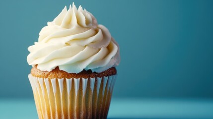 Macro shot of vanilla cupcake with white icing on blue background.