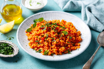 Bulgur Turkish style with tomatoes. Blue background. Close up.