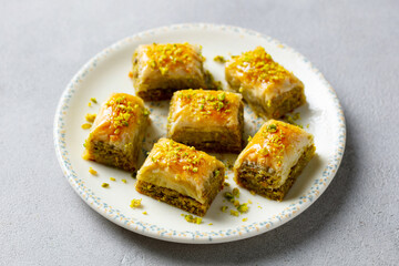 Turkish dessert baklava on a white plate. Grey background. Close up.