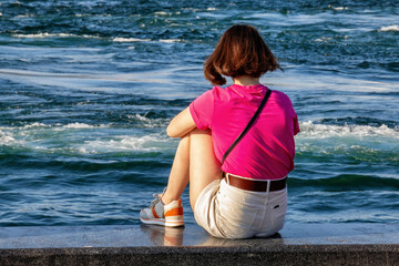 Unknown young woman sitting near the banks of the Golden Horn in the center of Istanbul.