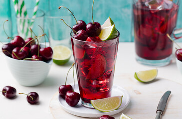 Cherry Limeade, lemonade, cola, cocktail in a tall glass. White and turquoise background. Close up.
