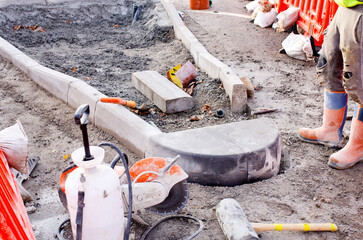 Construction workers laying concrete curb to improve road infrastructure and enhance pedestrian...