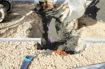 Builders filling trench with concrete on building site