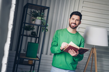 Fototapeta premium Young man in a casual setting reading a book in a cozy, stylish interior with bright lighting