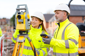 Construction team engages in surveying activity wearing safety gear at a building site 