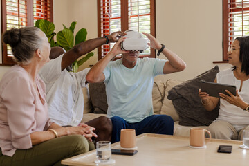 Senior friends exploring virtual reality headset together in cozy living room setting