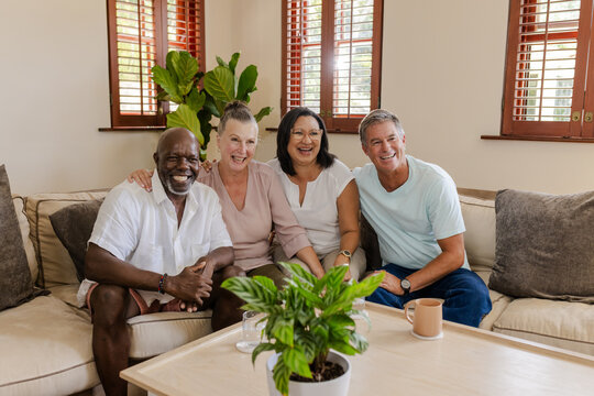 Senior Friends sitting on sofa at home, laughing and enjoying time together