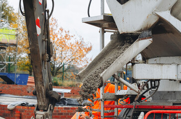 Construction workers pour concrete for a foundation at a building site