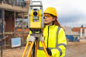 Young woman surveying a construction site using total station equipment