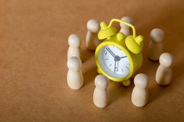Time Management and Teamwork Concept with Wooden Figures and Alarm Clock