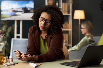 Young pretty businesswoman making manicure at the table during break in office