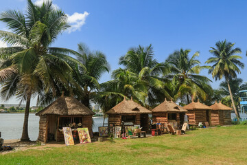Artisans showcase their crafts near traditional huts along the river in Abidjan, Ivory Coast