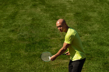 Strong caucasian badminton player racquet hit shuttlecock while practice before competition. Summer sports game, outdoors. Game moment.
