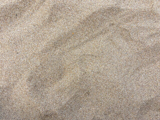 Detailed view of sandy beach texture showcasing fine grain patterns and natural colors