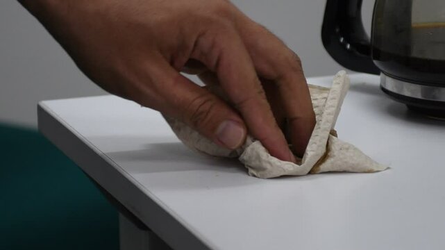 Cleaning spilled coffee from a table with a cloth, wiping liquid mess, coffee spill cleanup. High quality 4k footage