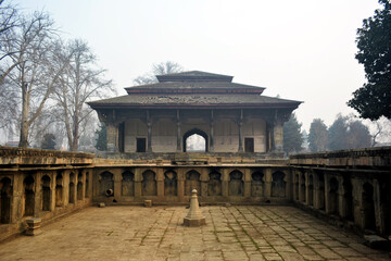 Fototapeta premium Shalimar Bagh's historical pavilion with arched entrance, surrounded by a detailed stone courtyard. Architectural scene, cultural heritage, and travel photography. Serene and timeless beauty