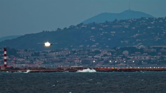 Airplane landing at the Nice Cote d'Azur Airport, France in the evening with the mountains on the background