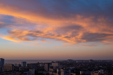 Fototapeta premium City skyline at sunrise with colorful clouds over the ocean. Urban landscape with residential buildings and scenic sky. Coastal town view in the morning