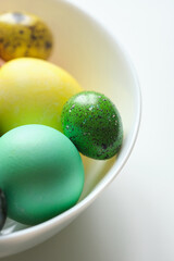 Colored easter eggs in white bowl close up macro