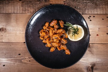 Tempting Teriyaki Mussels with Lemon and Rosemary on Black Plate, Aged Wood Backdrop, Texture Focus.