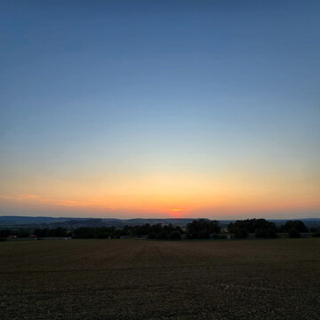The serene sunset over tranquil fields is beautifully captured in its stunning splendor Deister Bad Nenndorf
