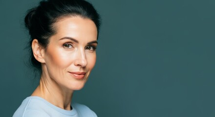 Confident caucasian mature female with dark hair in blue sweater against green background