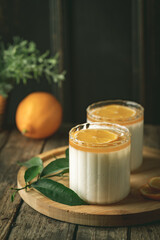 Homemade dessert panna cotta, mousse or pudding in a portion glass with lemon curd and fresh lemon.