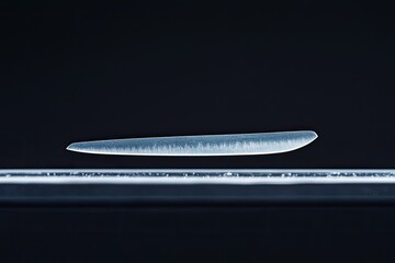 monochrome macro shot of scalpel blade resting on surgical tray with precise textures highlighted