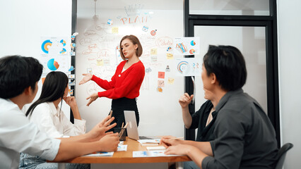 Young beautiful leader presents marketing strategy while expert investor and project manager listening and lecturing to analyze business performance at start up business meeting. Immaculate.