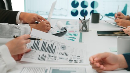 A diverse business team engages in a collaborative meeting focused on data analysis and strategic planning, surrounded by charts, graphs, and interactive reports. SACTR