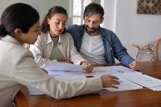Financial advisor giving consultation to customers, showing analytics on paper diagrams, discussing saving strategy, insurance program. Broker presenting investment plan to couple - Powered by Adobe