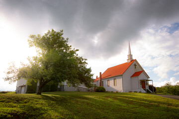 Fototapeta premium Church landscape with light breaking out from behind clouds