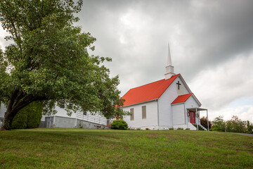 Fototapeta premium Church on hill with clouds in sky and green trees