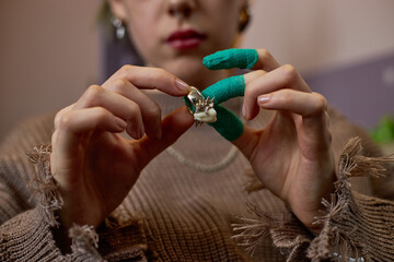 Skilled craftsperson with gloved hands meticulously creating intricate floral design on jewelry...
