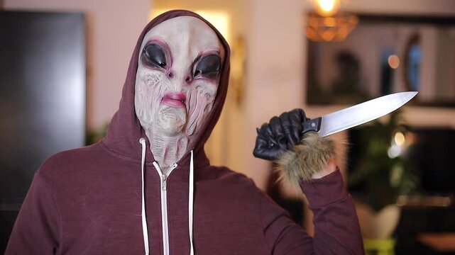 Person Wearing Alien Mask and Holding Plastic Knife for Halloween