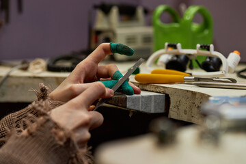 Zoomed-in view of hands sharpening knife on whetstone in cluttered workshop, showcasing intricate...