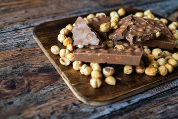 Chocolate bar with hazelnuts on rustic wood