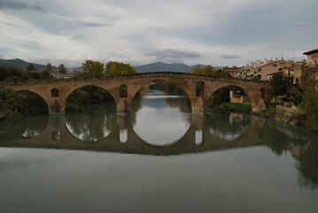 Obraz premium Puente de la Reina or Gares Bridge with its reflection in the Arga River, located in Navarra. The iconic Bridge of the Pilgrims of the Camino de Santiago Frances, route that comes from the Fances side