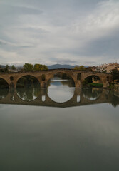 Fototapeta premium Puente de la Reina or Gares Bridge with its reflection in the Arga River, located in Navarra. The iconic Bridge of the Pilgrims of the Camino de Santiago Frances, route that comes from the Fances side