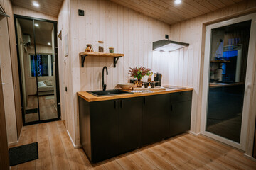 A modern kitchen with black cabinets, wooden countertops, and a cozy Scandinavian design, featuring warm lighting and decorative elements..