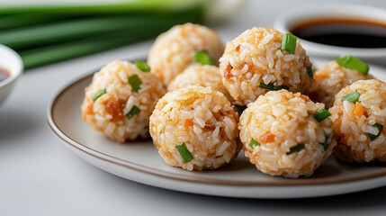 Crispy Chinese fried rice balls stuffed with pork and vegetables served on traditional plate with soy sauce and green onions