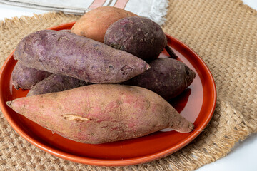 Colorful sweet-tasting tuberous roots vegetables purple and orange organic sweet potatos close up
