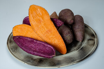 Colorful sweet-tasting tuberous roots vegetables purple and orange organic sweet potatos close up