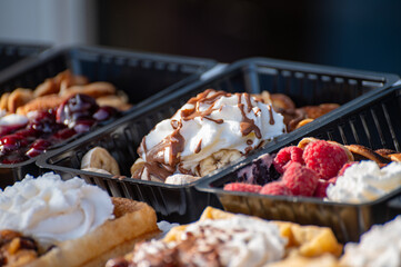 Variety of fresh baked waffles richly decorated with different toppings, sweet sweets, chocolate, cream, fruit and berries, jelly sweets in bakery with confectionery shop, old Volendam, Dutch sweets
